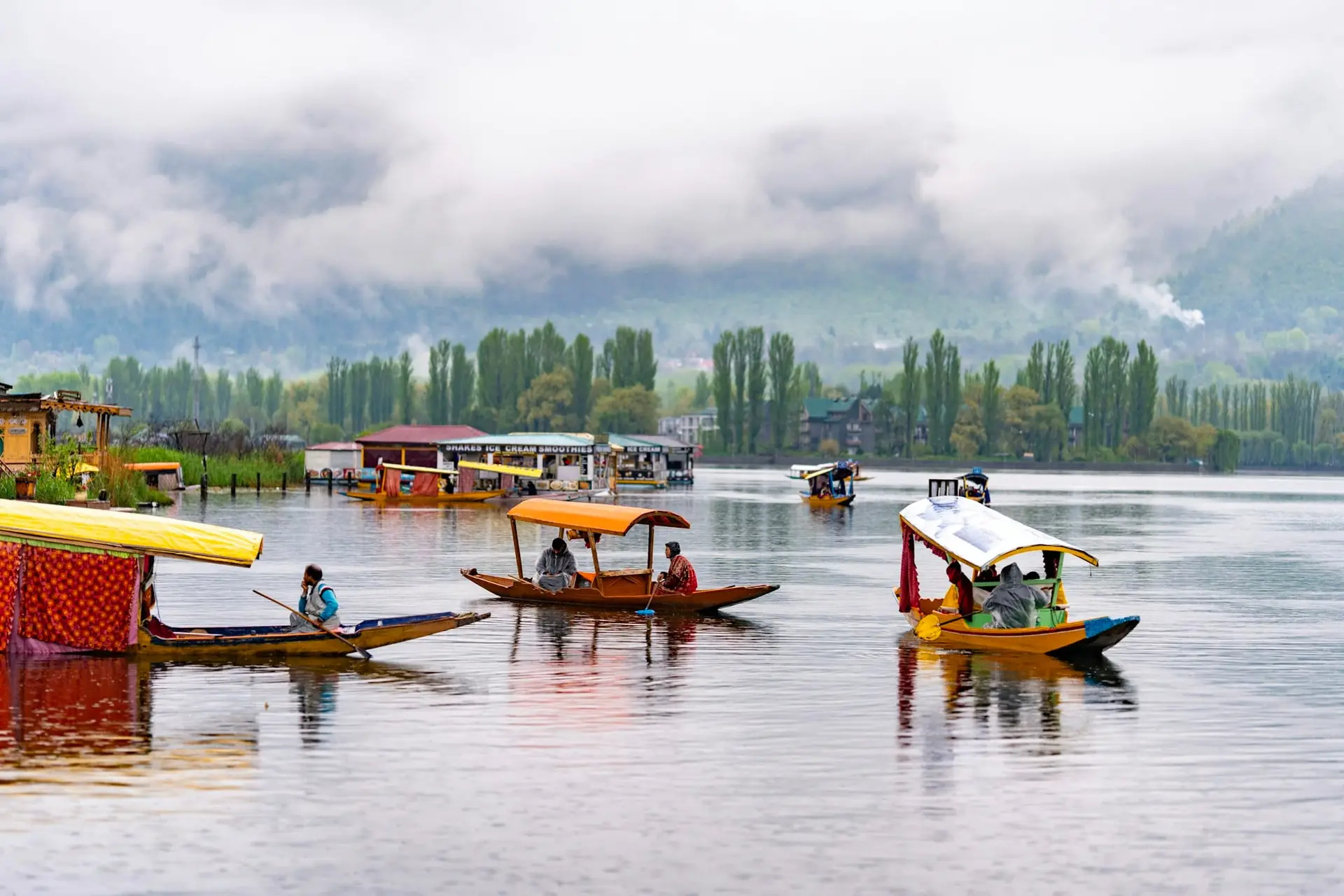 Shikaras waiting on the misty water of Dal Lake with mountains behind