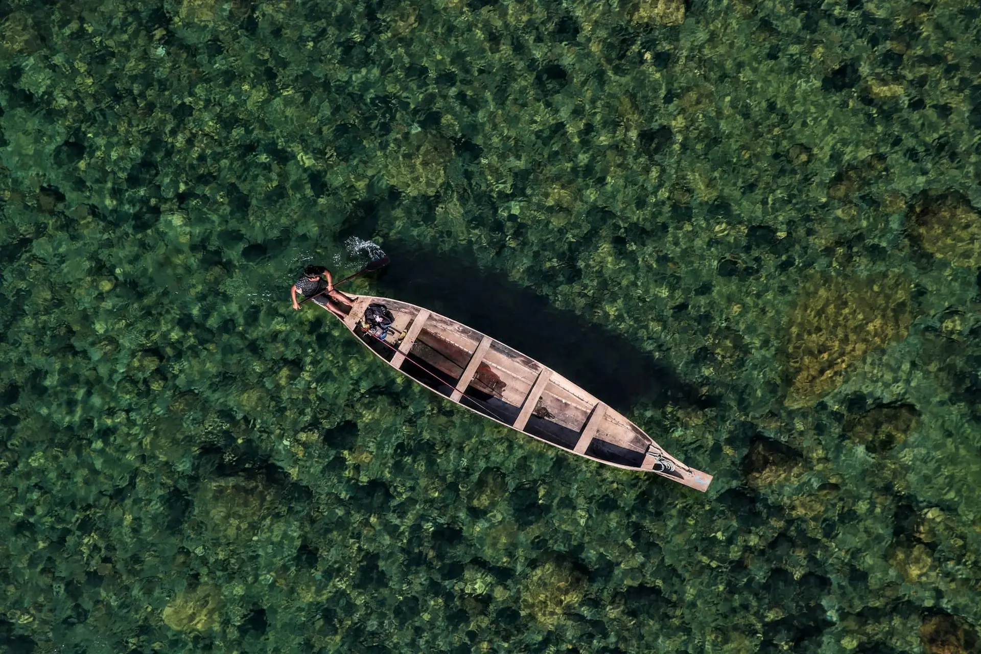 A single boat on the emerald water of the Umngot River, seen from above