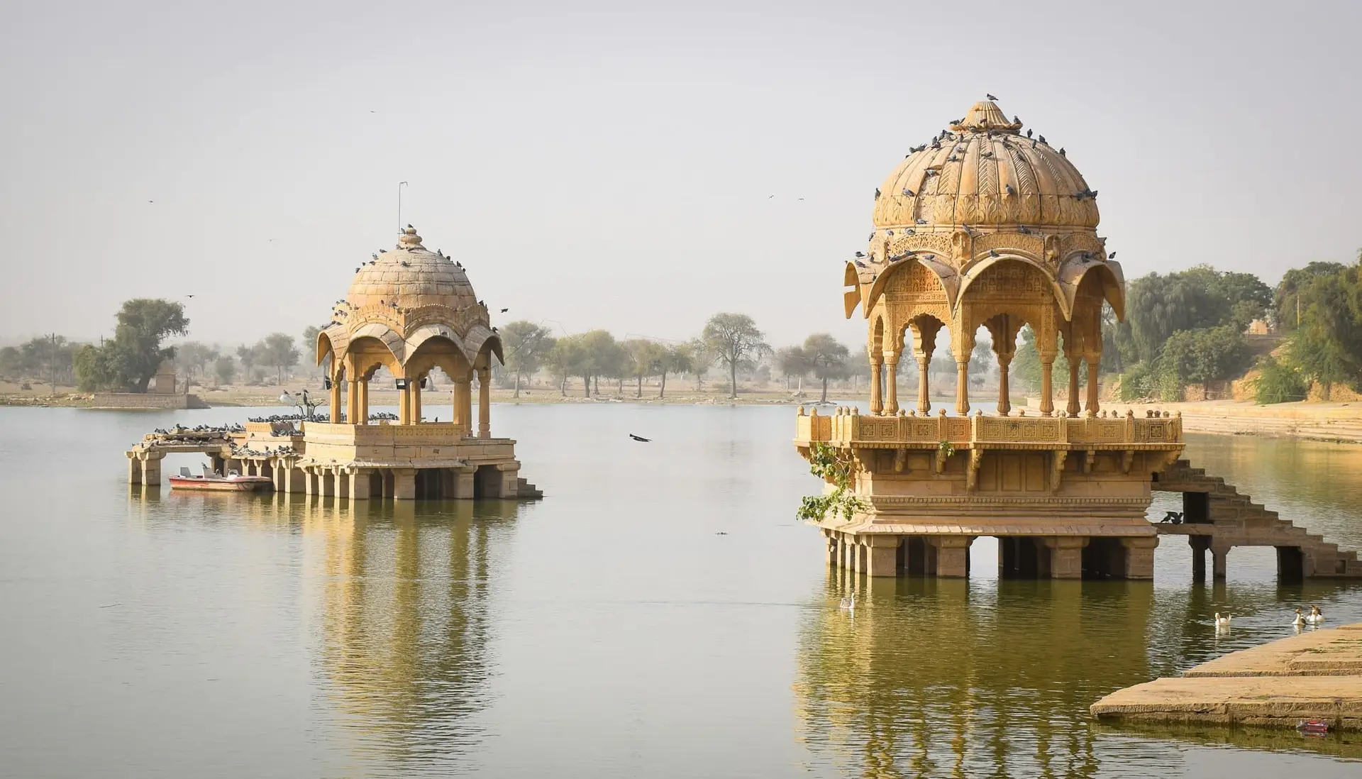 Carved sandstone pavilions on the still water of Gadisar Lake, Jaisalmer