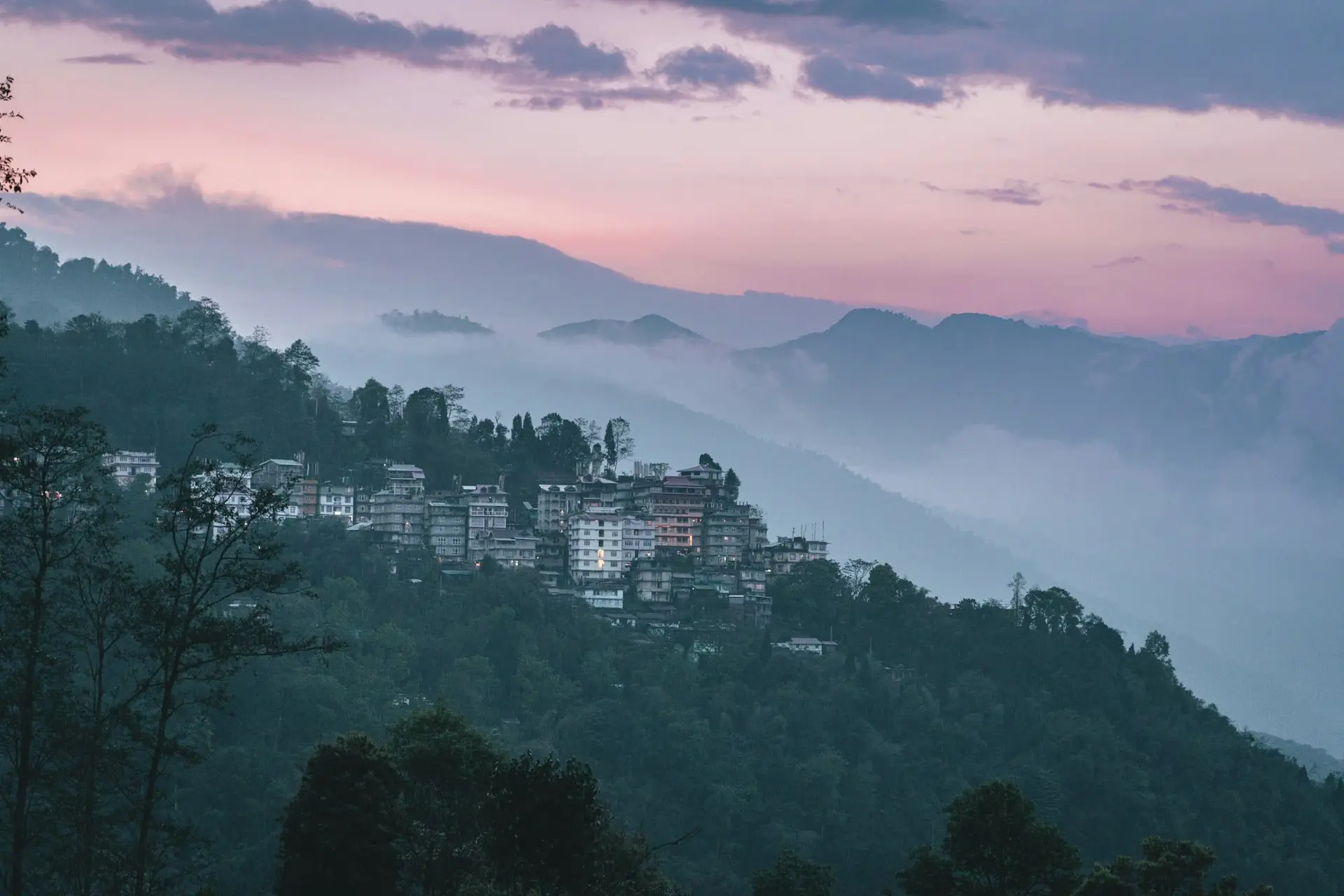 Houses scattered across a forested Himalayan ridge in Pelling at dusk